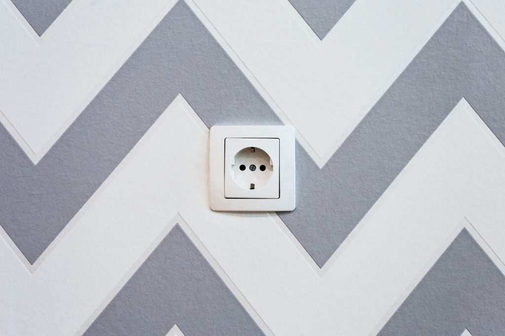 Geaard stopcontact met randaarde in een muur met zigzagbehang