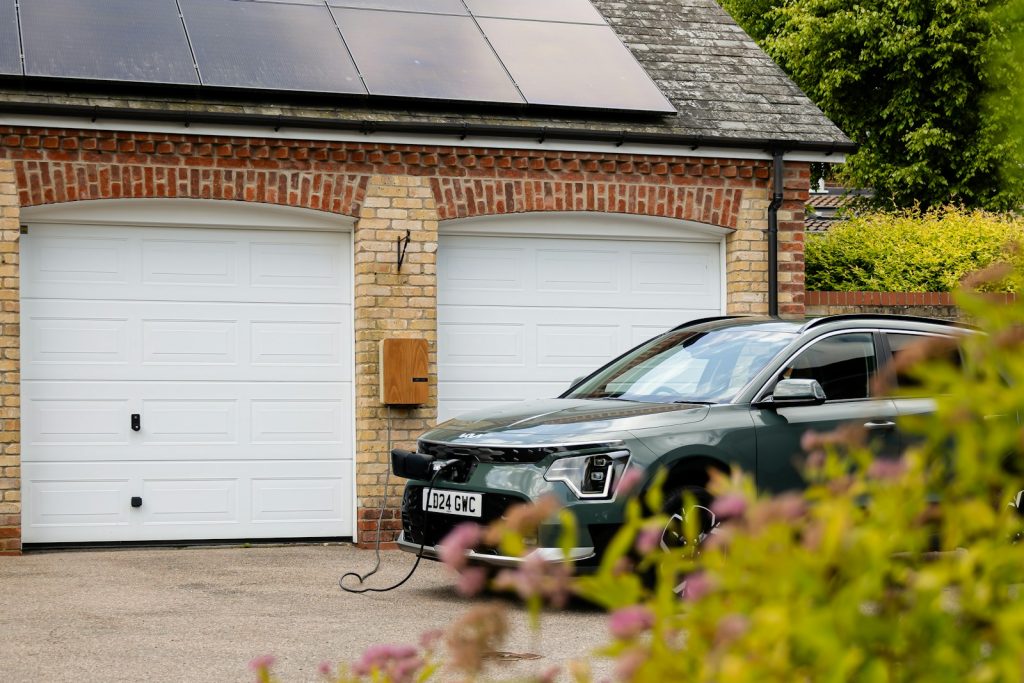 Woning met zonnepanelen op het dak en een elektrische auto aan de laadkabel voor de garage